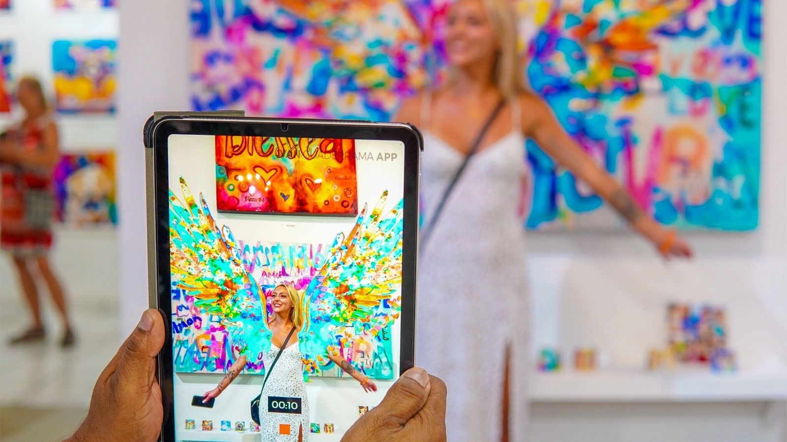 Gallery visitor experiencing Ivan Guaderrama's interactive Christian art through augmented reality on tablet — original AR painting comes alive in San José del Cabo gallery